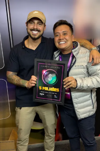 Caê Nonaka recebendo placa de premiação de 5 milhões